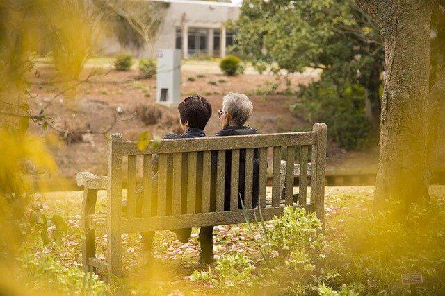 高齢者と一緒に並んでベンチに座っている女の人が写っている写真