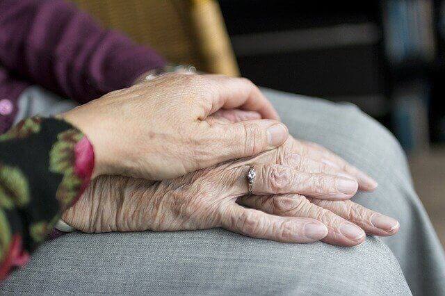 高齢の手に手を重ね合わせる介護者の手のアップの写真