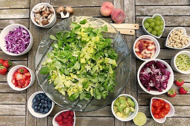 真ん中に青野菜の大皿とその回りに果物や野菜が刻まれた小皿の写真