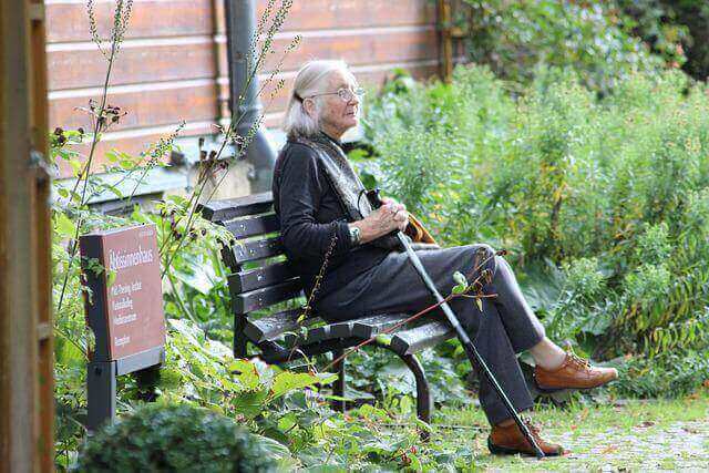高齢のおばあさんが公園のベンチで休んでいる写真