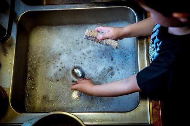 台所で子どもが洗い物のお手伝いをしている写真